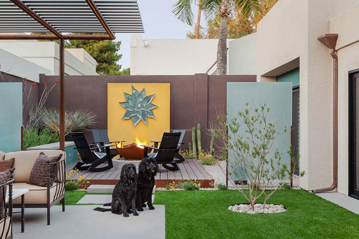 Two black dogs sitting in modern backyard patio.